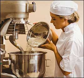 woman using commercial mixer in bakery or restaurant