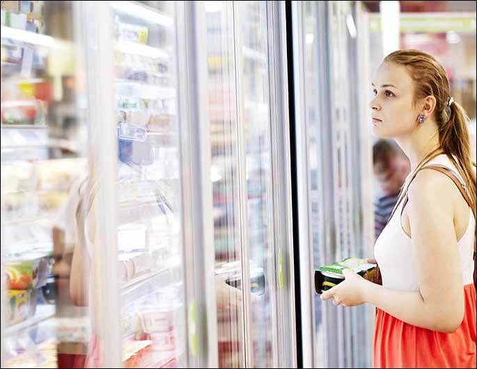 woman looking at selections in frozen food merchandiser