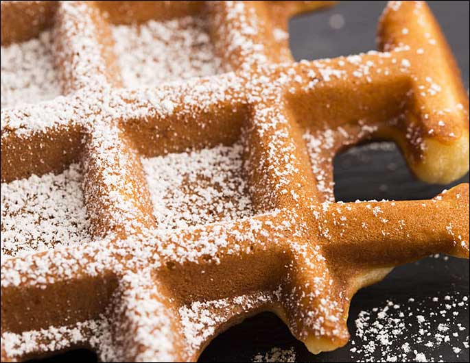 close up of waffle being cooked on waffle iron